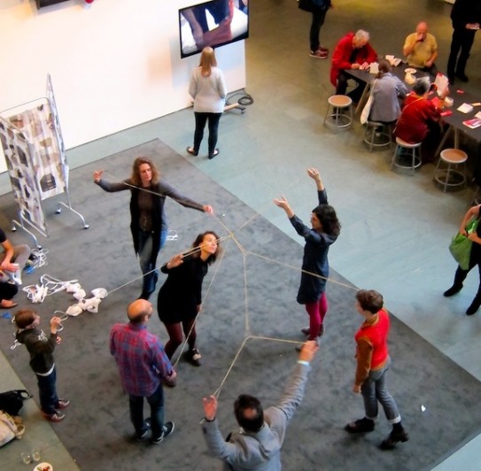 Visitors using Lygia Clark's sensorial object called Living Structures, made up of elastic bands connecting participants in a giant flexible web. Photo by Sarah Kennedy