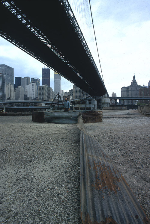 Richard Nonas with his installation beneath the Brooklyn Bridge. Unknown photographer. The Brooklyn Bridge Event, N.Y., N.Y. (May 24, 1971). Color slide. MoMA PS1, 2462. The Museum of Modern Art Archives, New York.