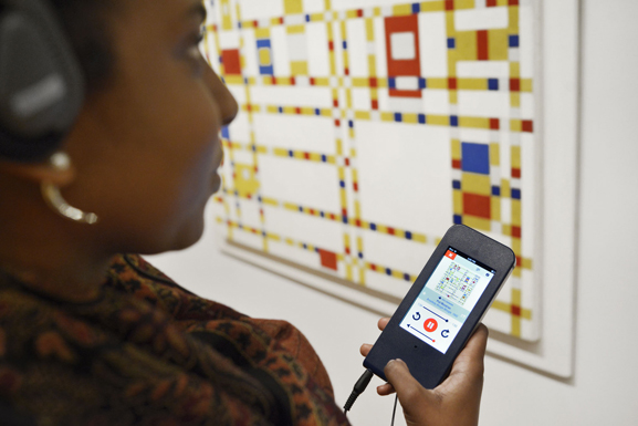 A visitor in the galleries using the MoMA Audio+ mobile guide. Photo: Martin Seck