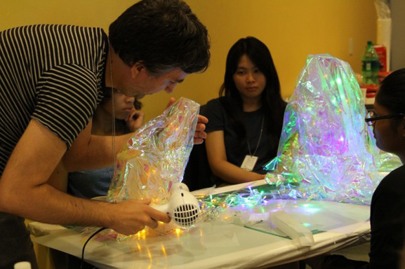 Babycastles member Robin Enrico assists teens with the production of the flashing crystals