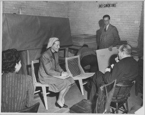 "Judging of the Competition Entries: Two Jurors, Catherine Bauer and Ludwig Mies van der Rohe, discussing an entry.Edgar Kaufmann, Jr., Competition Director standing in background." Publicity photograph released in connection with the exhibition, "Prize Design for Modern Furniture." 1950  