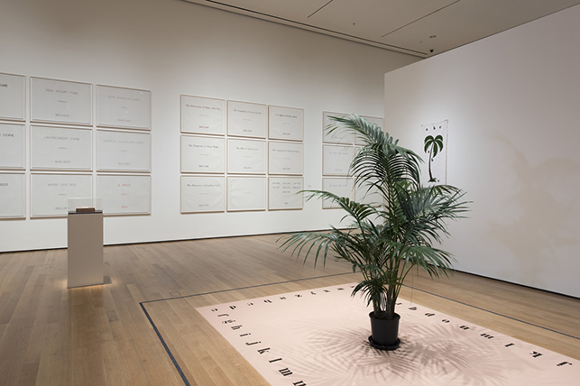 Marcel Broodthaers. Tapis de Sable (Sand carpet). 1974. Quartz sand, pigment, palm in pot, printed terry cloth towel. Installation view, The Museum of Modern Art, New York, February 14–May 15, 2016. Collection Van Abbemuseum, Eindhoven. © 2016 Estate of Marcel Broodthaers/Artists Rights Society (ARS), New York/SABAM, Brussels. Photo: Martin Seck