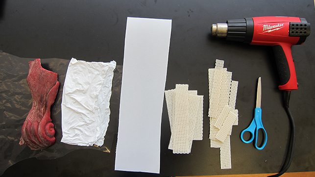 Supplies and test leg of wax (courtesy of Jeffrey Spring and Modern Art Foundry). This photograph includes (from left to right) the test wax, Teflon™ sheeting, two types of polycaprolactone, scissors, and the temperature control heat gun
